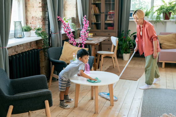 istock Young woman cleaning floor while her son wiping table with sanitizer 1358407978