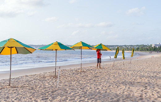 João Pessoa, Paraíba, Brazil - October 18, 2021:Man setting  parasols on the beach sand.