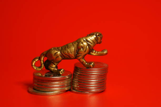 istock Metal tiger figurine with coins on a red background. 1358413222