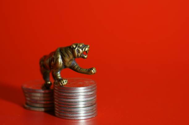 istock Metal tiger figurine with coins on a red background. 1358413224