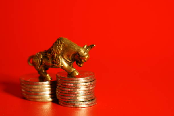 istock Bull figurine with coins on a red background. Close-up subjects. 1358413248