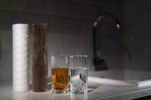 Filters for water. Water purification for domestic water supply. New clean and old dirty filter cartridge in rust. Rusty tap water. Plumber changes in bathroom or kitchen. Filtration. Glasses.