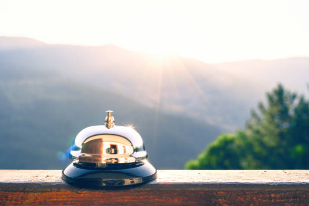 серебряный винтажный колокол на деревенской стойке регистрации в утренней горе восход солнца. эко, кемпинг гостиничный сервис, регистраци� - hotel reception bell hotel service bell стоковые фото и изображения