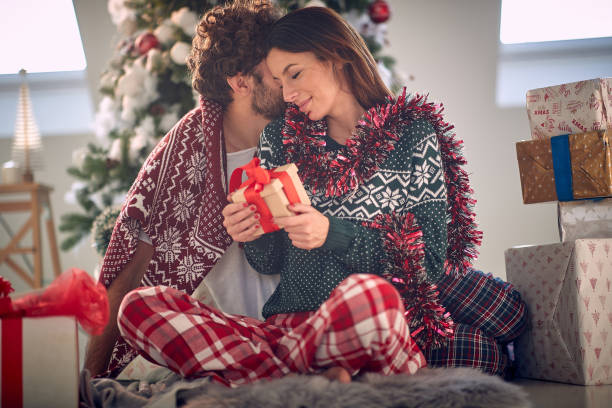 istock Romantic Couple hugging around christmas tree at home 1358420345