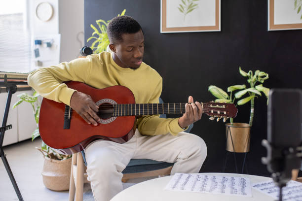 istock Young serious African man playing guitar in front of smartphone camera 1358422596