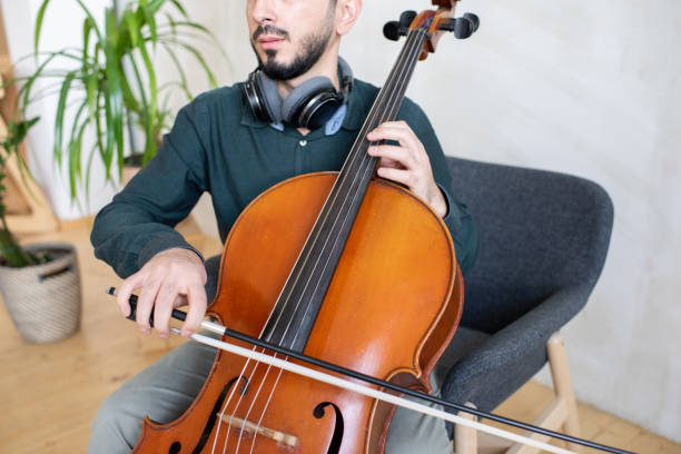 istock Contemporary young man gliding fiddlestick against strings of cello 1358422632