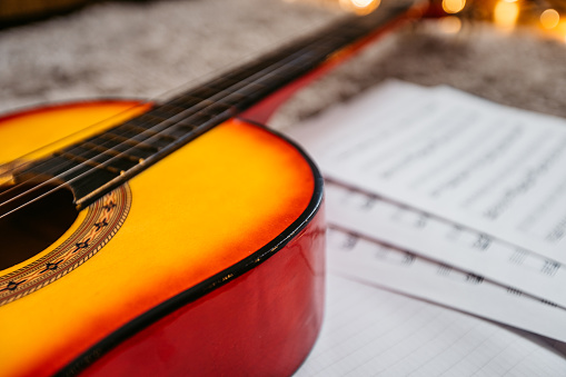 A close-up of a red yellow guitar with music notes in the background.