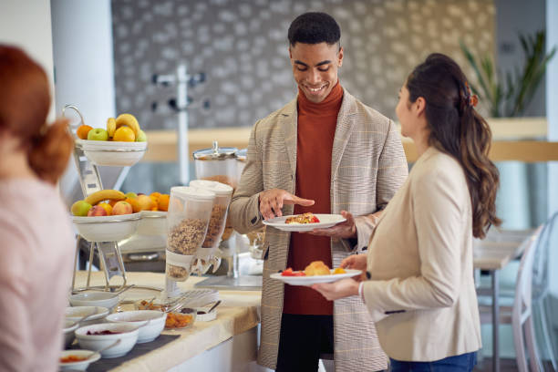 istock A young man is having a friendly conversation with female colleague while helping themselves with a food at the lunch break during a business conference. Business, people, meeting, company 1358424254