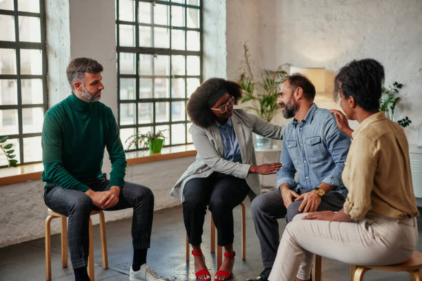 Multiracial therapy group during pandemic Middle age man sharing struggles during support group meeting with multiracial people siting in circle and comforting him group therapy stock pictures, royalty-free photos & images