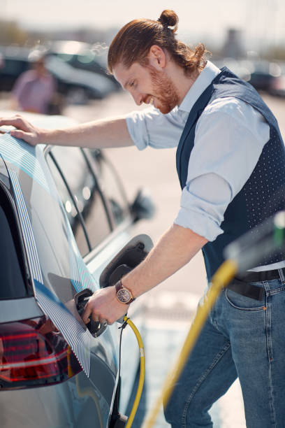 istock Modern busnessman charging his electric car 1358426290