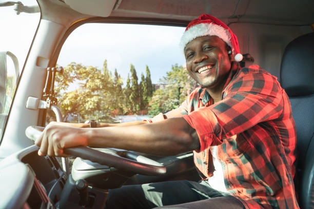 happy Smile Confidence Young Man Truck Driver In Business Long transport. Smile Confidence truck driver wear Santa Clause hat driving semi-truck In Business Long transport. Trucker lifestyle young man African American working holidays.  Merry Christmas and happy new year. wheel cap stock pictures, royalty-free photos & images