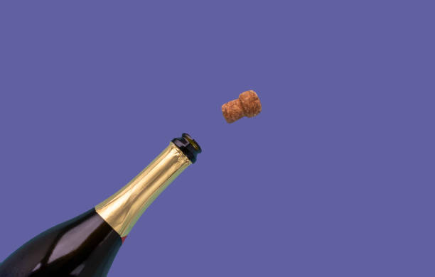 A bottle of champagne and a cork are open on a very peri lilac background A bottle of champagne and a cork are open on a very peri lilac background. cork stopper stock pictures, royalty-free photos & images