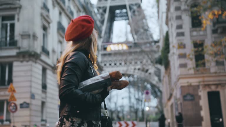 SLO MO French woman in leather jacket carries baguettes down the street along the Eiffel Tower