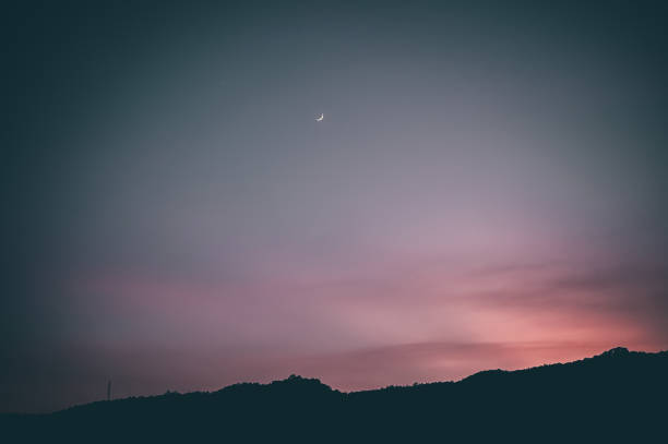 istock Golden hour beautiful red sky with crescent moon and silhouette mountain range 1358437304