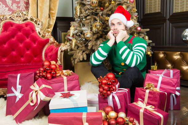 istock Man with present boxes at christmas tree. Man prepare present packs on new year eve. Man in santa costume celebrate new year. Santa stops here 1358438169