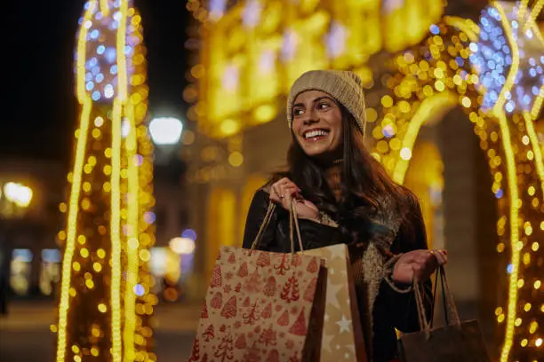 Woman enjoy in shopping, she walking through city and holding shopping bags with christmas gifts.