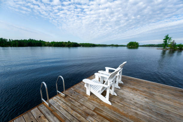 istock Two white Adirondack chairs on a wooden dock 1358444695