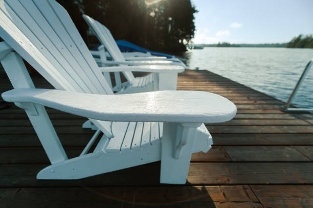 istock Close-up on two White Adirondack chairs on a wooden dock 1358444821
