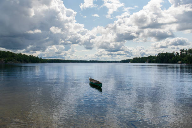 Green canoe tied to the shoreline on a lake in Muskoka - Ontario, Canada