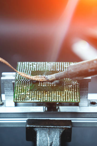 istock Soldering iron and copper wire to remove excess solder from the laptop processor 1358446038