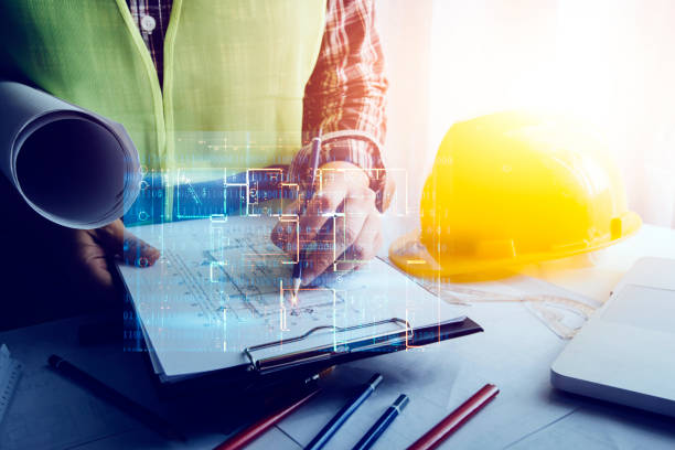 istock Two colleagues discussing data working and tablet, laptop with on on architectural project at construction site at desk in office 1358446365