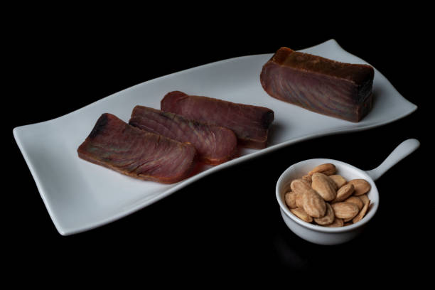 diversi pezzi di tonno a scatti (mojama) su un piatto accompagnato da mandorle salate. - tuna steak fillet food plate foto e immagini stock