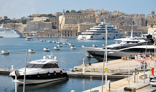 Superyachts in Birgu harbour, Valletta, Island of Malta, Mediterranean Sea. The sprawling Malta  harbour districts play host to numerous superyachts and other pleasure craft. Malta is a central Mediterranean archipelago between Sicily and the North African coast,  known for its mellow sandstone architecture and historic sites reflecting the styles of rulers that include the Romans, Moors, Knights of Saint John, French and British