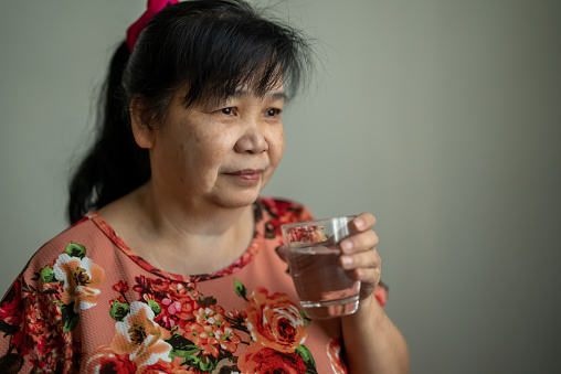 Senior Asian woman drinking water at home in the morning, Happy and smiling