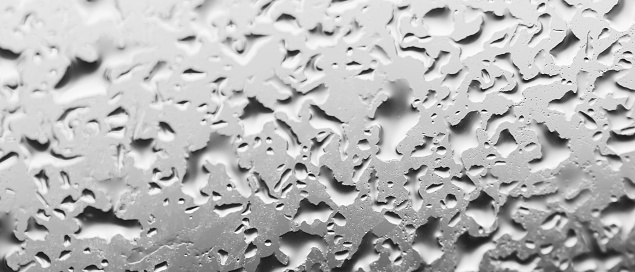 Water drops behind glass. Background from raindrops on the window. Black-and-white backdrop made of drips of water. Creative pattern