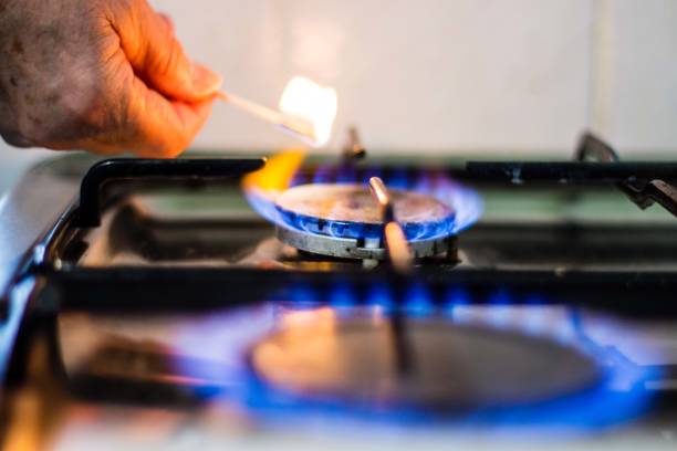 chama de gás em um topo de fogão iluminado por um fósforo para cozinhar - house burning color image danger - fotografias e filmes do acervo