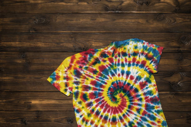 istock Spiral tie dye pattern on a T-shirt on a wooden background. Flat lay. 1358458400