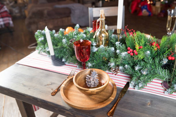 istock Elegant Christmas dinner table setting. Decoration of Christmas table: candles, juniper branches and napkins, wooden plates. New Year decorations in living room.country style. 1358460662