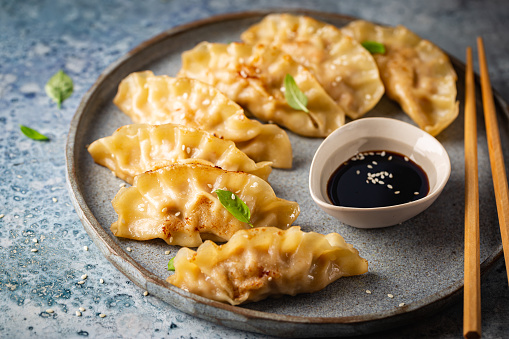 Asian dumplings with soy sauce, sesame seeds and microgreens. Traditional chinese dim sum dumplings.