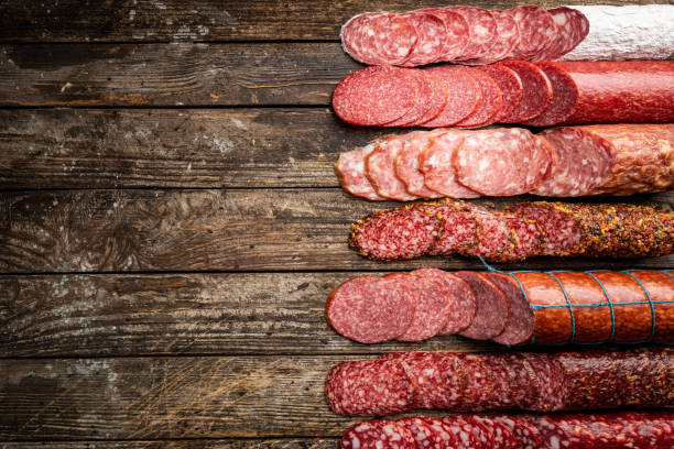 Set of different types of sausages Set of different types of sausages, salami and smoked meat with basil and spices on wooden background. Top view. salami stock pictures, royalty-free photos & images