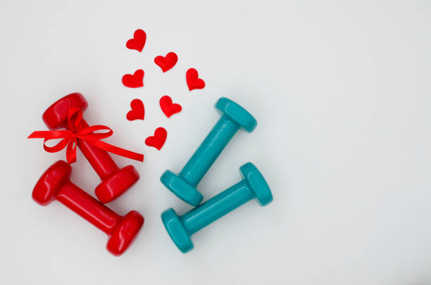 istock Two turquoise, red dumbbells with ribbon, hearts on white background with copy space. Concept Valentines day, male and female, healthy lifestyle, giving gifts, love of sports. Trendy color green tide 1358464663