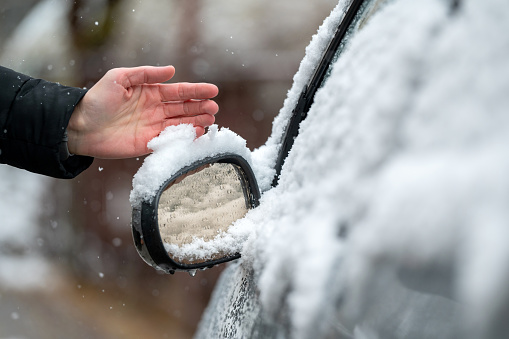 Close up shot of a side mirror of a car covered with a snow during winter time