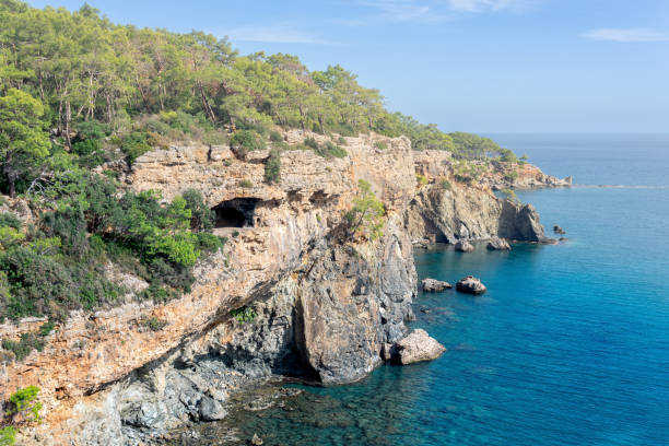 istock Mediterranean seascape with steep wooded coast with cave 1358468253