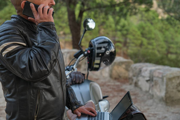 istock Digital nomad with laptop talking on the phone while traveling on motorcycle 1358468347