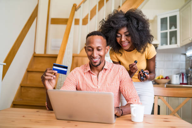 istock Young multiracial couple  using laptop on their kitchen table- couple in love having breakfast together and making online shopping by laptop and using credit card 1358468538