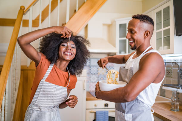 istock Playful multiracial couple eating pasta for dinner in small kitchen. 1358468554