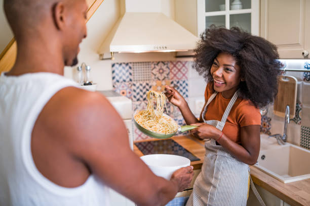 istock Young multiracial couple having romantic evening in a small kitchen, cooking pasta together 1358468563