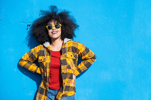 Smiling american-african woman standing on a blue background