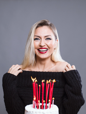 Beautiful woman celebrating her birthday holding birthday cake with candles