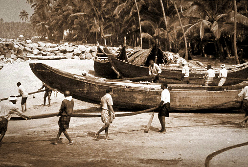 Alappuzha, Kerala, India - circa oct 1975: fishermen retrieve the seine nets by pulling them from the beach. Historical black and white photo.