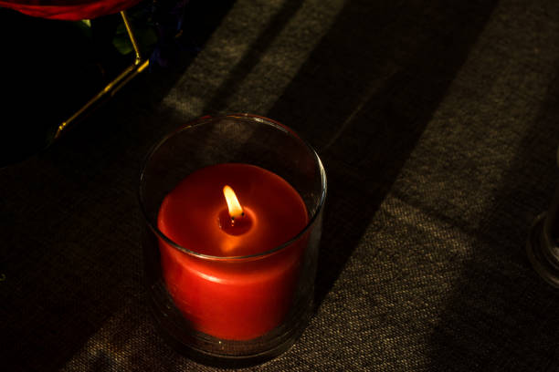 Lit red candle in a  glass container.