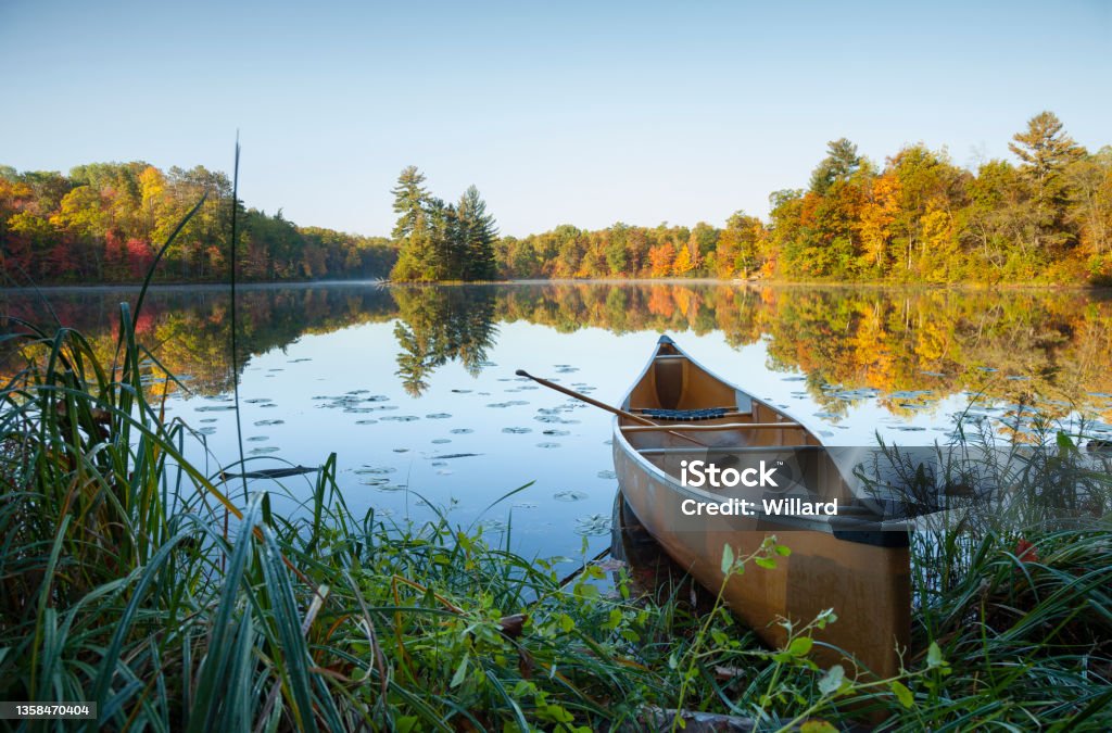 Canoe with paddle on shore of beautiful lake with island in northern Minnesota at dawn Canoe with paddle on shore of beautiful lake with island in northern Minnesota at sunrise Landscape - Scenery Stock Photo