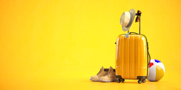 Yellow suitcase with boots, hat and sun glasses on yellow background. Travel and tourism concept, stock photo