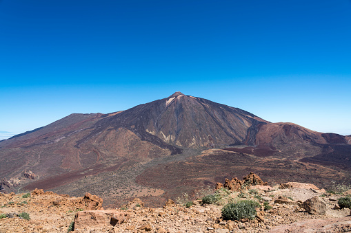 Volcanic pick from high up the mountain opposite.  El Teide National Park, Tenerife (Canary Islands).  El Teide against clear blue sky on sunny day.