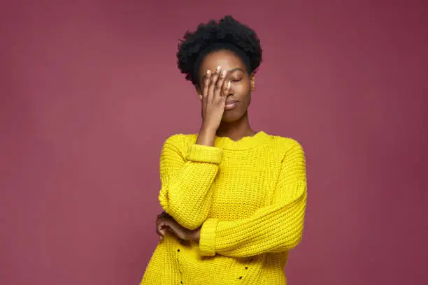Upset african american young girl with facepalm gesture, blaming herself, feeling sorrow because of bad memory. High quality photo