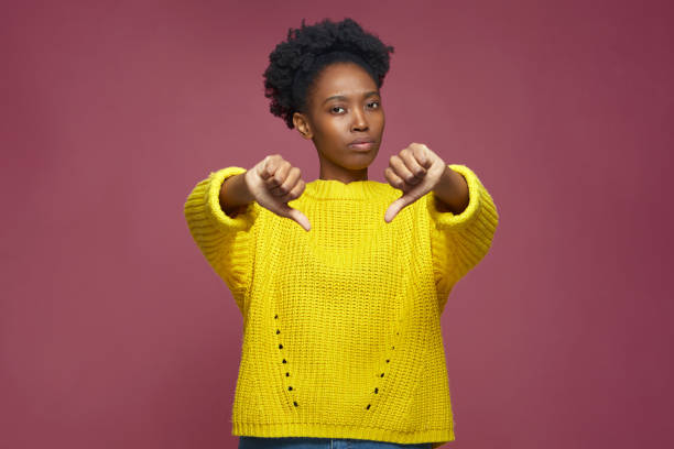 Dissatisfied young african american girl thumbs down gesture, negative feedback, dislike, disagreement, rejection sign Dissatisfied young african american girl showing thumbs down gesture, negative feedback, dislike, disagreement or rejection sign. High quality photo thumb down stock pictures, royalty-free photos & images